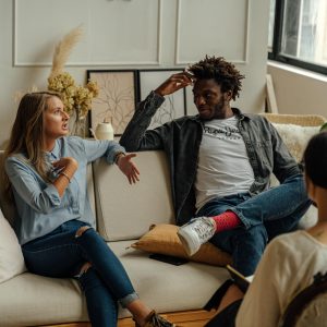 Couple sitting on a couch speaking to a therapist