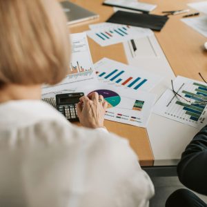 Woman with blonde hair looking at various financial paperwork on a table